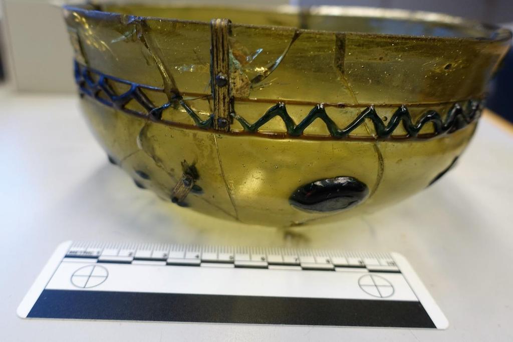 Figur 4: Glasskål fra Hogstad (S1526). Et dekorert bånd har gått rundt hele randen, festet med beslag som er naglet fast i glasset. Nedenfor beslaget synes en annen reparasjon.