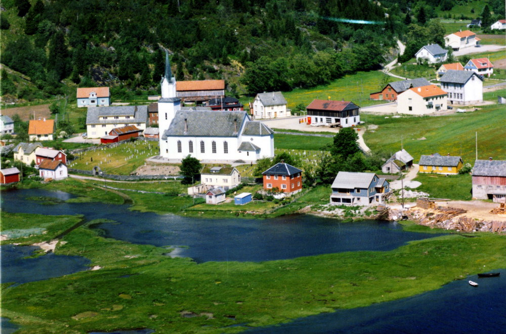 "13 Fjæra tidleg 1960.jpg" Naustdal sentrum tidleg 1960-åra, med Naustdal Kyrkje som var ferdig 1891. Den har 8-900 sitteplassar.