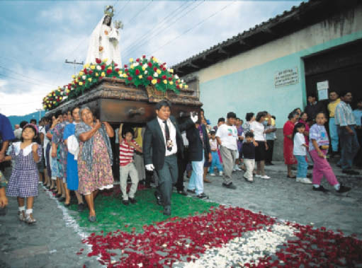 Religiøst opptog, Antigua, Guatemala. Han begynner å gå rundt bordet mens han snakker i rivende fart. Av og til går han bort til veggen, former bilder og situasjoner, tegner imaginære kart. Ser du?