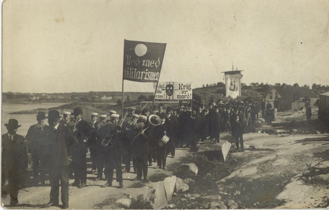 Foto 6: 1. mai toget på Spjærøy i 1912. Årets parole var ned med militarismen, som en reaksjon på Stortingets ekstraordinære bevilgning på 16 millioner kroner til militærbudsjettet.