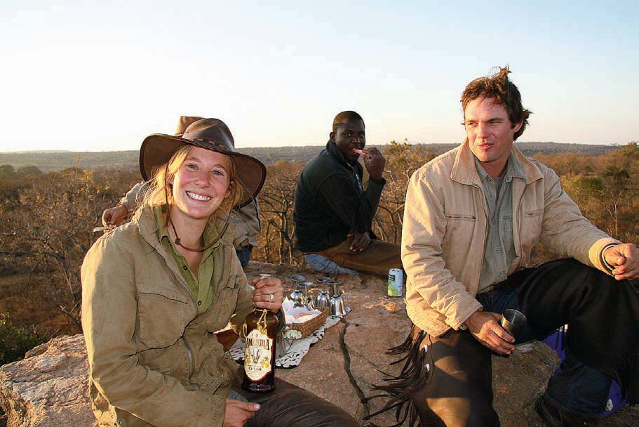 Neida, det er ikke de tre små griser som bor her. dett er Under: Saskia med et godt grep om den nasjonale festdrikken amarula. Freddy og Kobus nyter også safaripausen.