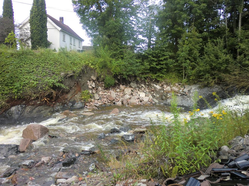 Mur etter flommen Eksisterende betongmur er undergravd og skadet på flere steder langs gammelt uthus.