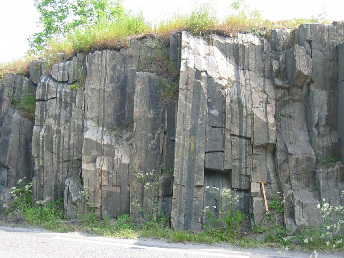 Figur 32 a: Veiskjæring i Havreåker-Burval sonen langs Herre-veien 500 m SØ for Burval. Bergarten er grå granittisk gneis med tynne bånd av amfibolitt og en velutviklet planstruktur.