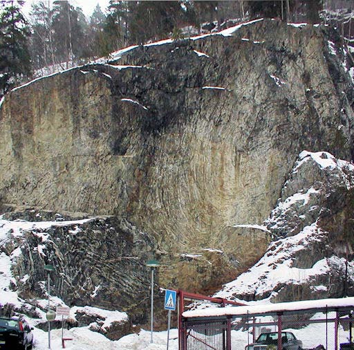 Nordmarkitt-gang (rødlig) gjennomsetter et bruddstykke av rombeporfyr (grålig med hvite spetter) i det øvre steinbruddet ved Stig. Foto: Tom V. Segalstad.