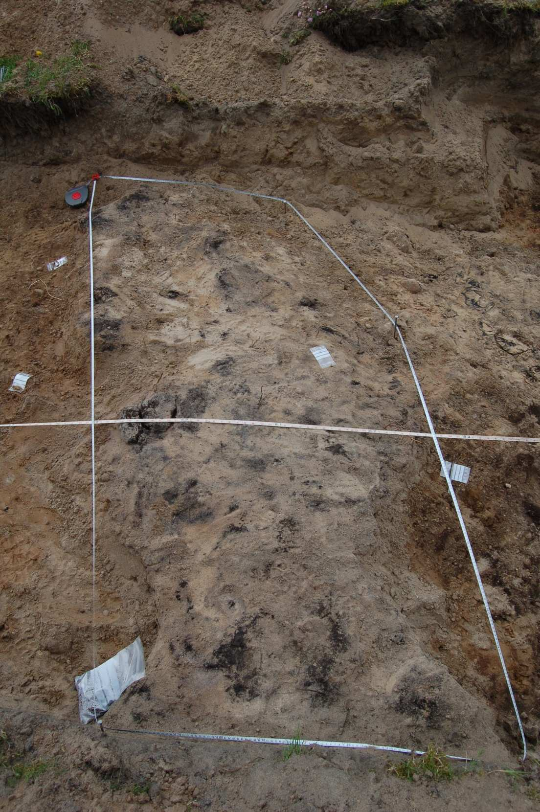 12 a) b) Figur 10 (sjakt 1): a) funn #64; fragment med retusj, b) funn #69; kjernestein. Struktur 4: vegg: 1 x 2.5 meter. Kullag blandet med sand og formulerer en vegg.