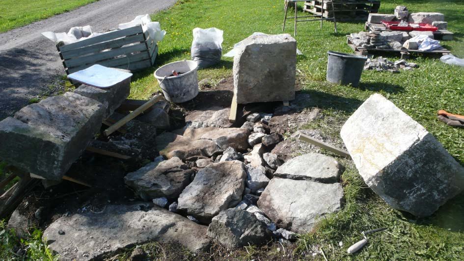 Fundament ferdig renset for betong og jord. Steinsatt mellom større stein. Sett fra nord.