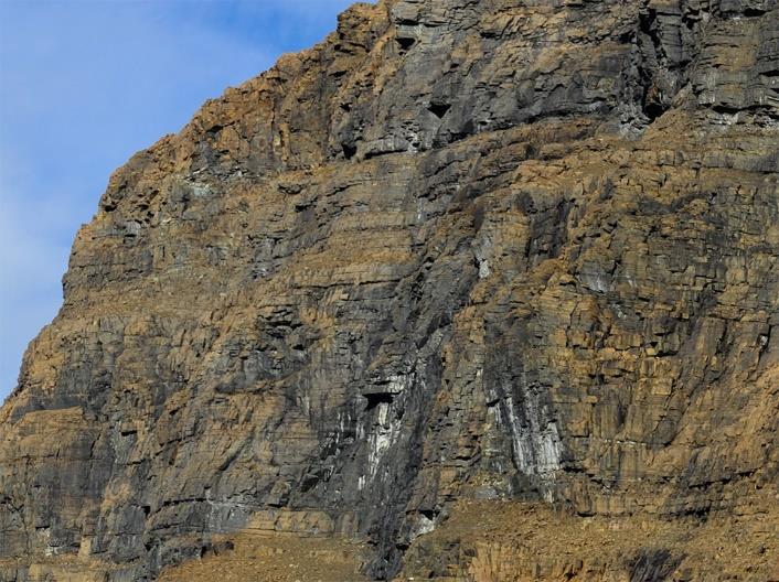 Gabbro can be seen as a bright rock in the lower left. Figur 4.5: Nærbilde av fjellsiden fra figur 4.4. Bildet viser lagdelingen i ULS.