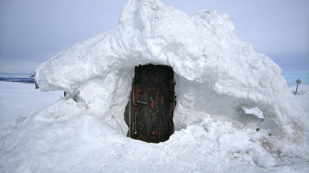 3 Bilde 1: Hytta på Neveltoppen i vinterskrud. Bildet er tatt før noen fant på at ståldøra var egnet som oppslagstavle og hyttebok.