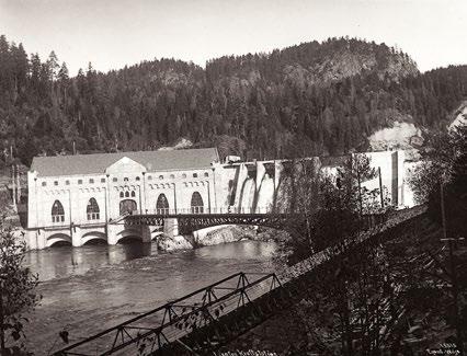 Lienfos kraftstasjon med atkomstbru i 1911, sett fra østsiden, og stedet i dag sett fra gulvet i den revne bygningen. Foto til venstre: Anders B. Wilse. Foto til høyre: Trond Taugbøl.