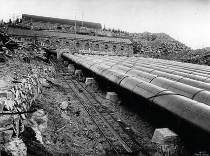 røret har diameter 2000 mm og er sveiset i hele lengden. Rørene er forbundet med klinkete muffer. Det er montert trallebane på rørgata. Vemork med rørgate i 1910. Foto: Auguste Léon. 3.