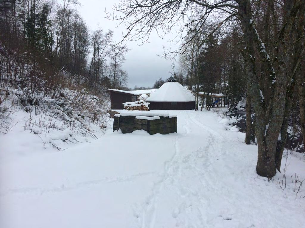 Uteområde bak lavvoen med skotthyllbane og utedo kan skimtes i bakgrunnen.