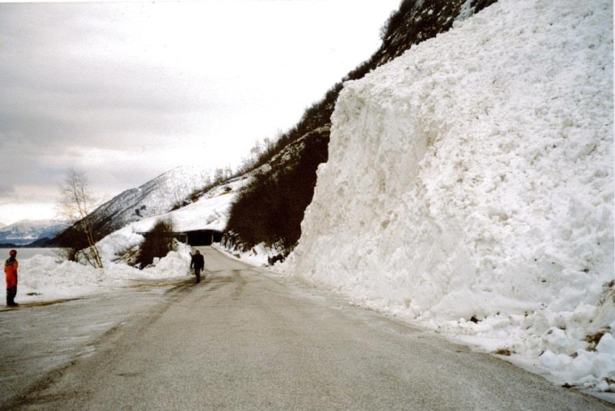 Figur 22.2 under viser at snøskred kan avsette store mektigheter på vegen, noe som vil gi lang stengningstid på grunn av opprydningsarbeid. Vegen blir også stengt på grunn av fare for snøskred.