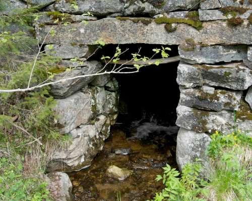 Gjennom Fv30 er bekken lagt i rør, før den går åpent ned skråningen mot jernbanen. Under jernbanen går bekken gjennom en kulvert av stein, før den igjen går åpent ut i Gaula. Figur 6.13.