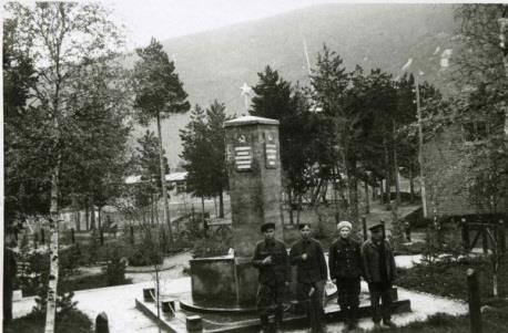 Bilde: Juni 1945. Foto av fire tidligere fanger foran den nybygde minnestøtten i Beisfjord. Foto fra T. Furunes. Kilder: Mladjenovic, Ljubo. Beisfjordtragedien. Oslo 1988.