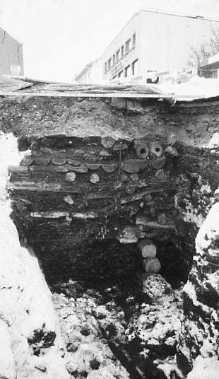 Figur 6 8. Til venstre kulturlag i Møllegaten, fra en utgraving i 1977. Stratigrafien viser tydelig kulturlag med deler av bryggeanlegg fra 1100 tallet nederst.