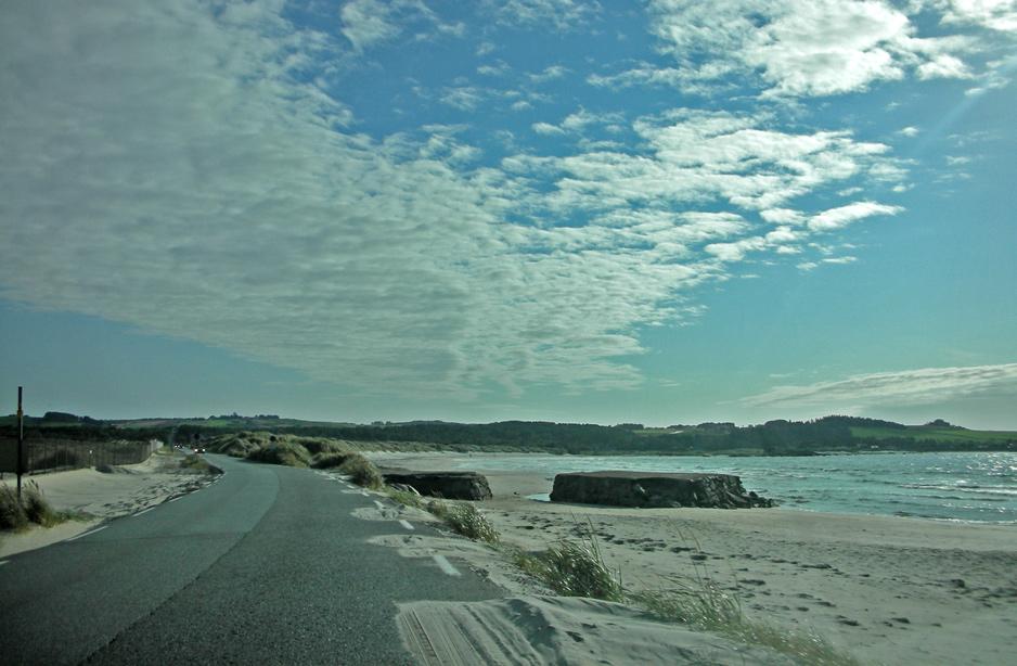 Ved Solastrandas midt, brytes de høye sanddynene, og landflaten glir så og si