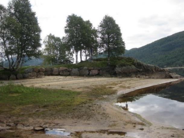 Figur 22: Bildet viser sandstranden på sørsiden av neset. Området med benker og bålplass ses i bakgrunnen. Figur 23: Adkomst ned til badestranden.