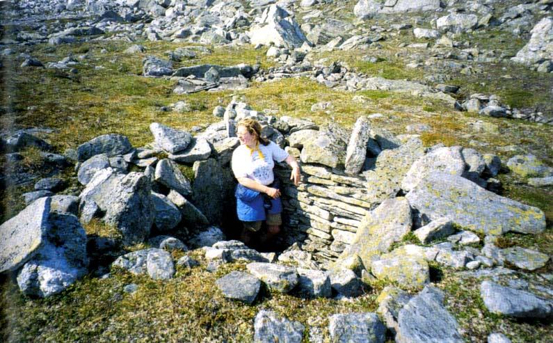 Marianne Strand i godt bevart dyregrav i Ytste Bortre Ramnåløyfta. Restane etter leiegardane som skulle føre reinsdya ned i dyregrava, er tydelege ved denne grava.