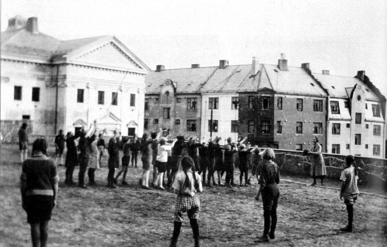 Kroppsøving for jenter, Aspøy skole, Ålesund, 1947-48. Frk. Borghild Maaseide, til høgre, held ballen. Ho var m.a. kroppsøvingslærar, og hadde studert moderne gymnastikkundervisning i Finland.