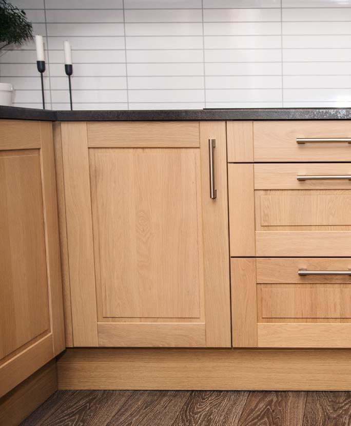 Her vises kjøkkenet med gråbrun benkeplate, håndtak i børstet stål og kitchen board i