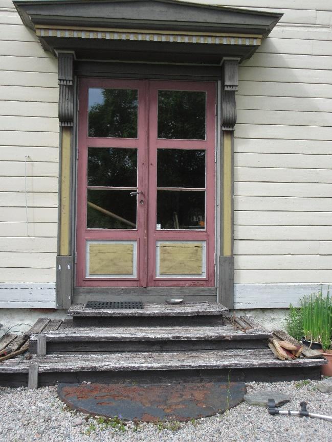 Sørsida av huset - fasaden Hageutgangen: Er nå ei tretrapp med to opprinn. Størst platting på øvre trinnet. Merker etter verandautbygg over hageinngangen kan sees på husets fasadevegg.