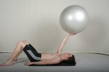 Koordinasjonstrening med fitnessball Utøver ligger på rygg mens han balanserer ballen.