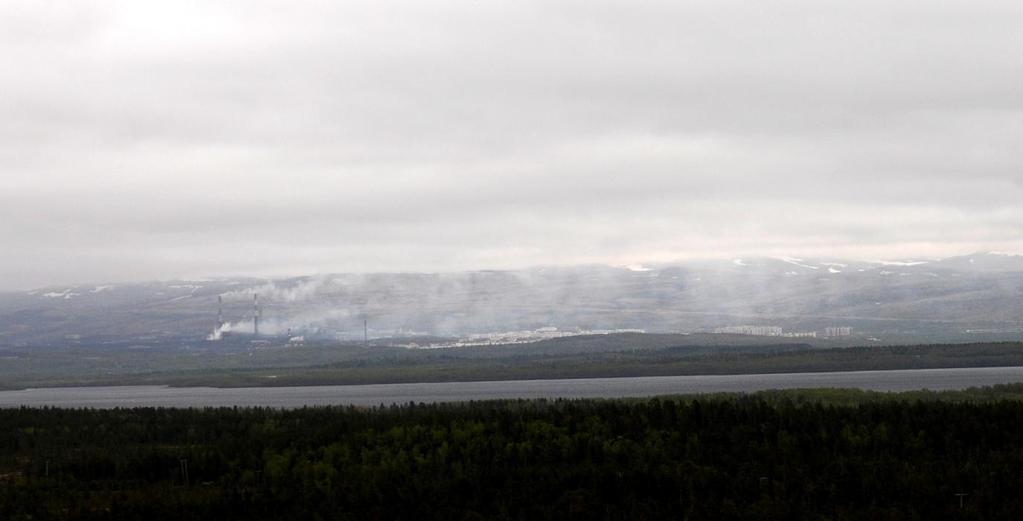 Figur 4: Smelteverket og Nikel by, sett fra høyde 96 i Pasvikdalen 19. juni 2008. Pasvikvassdraget og Svanevann skiller Norge og Russland. Nordlig vind bringer utslippene inn mot Nikel by.