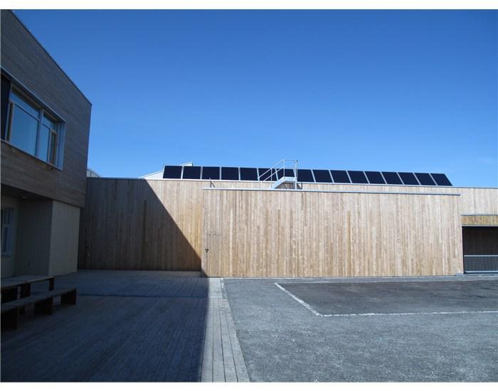 Figur 6: Solfangere for oppvarming av dusjvann til 6 idrettsgarderober er montert på taket av flerbrukshallen. Bildet viser den fremste av tre rader med solfangere.