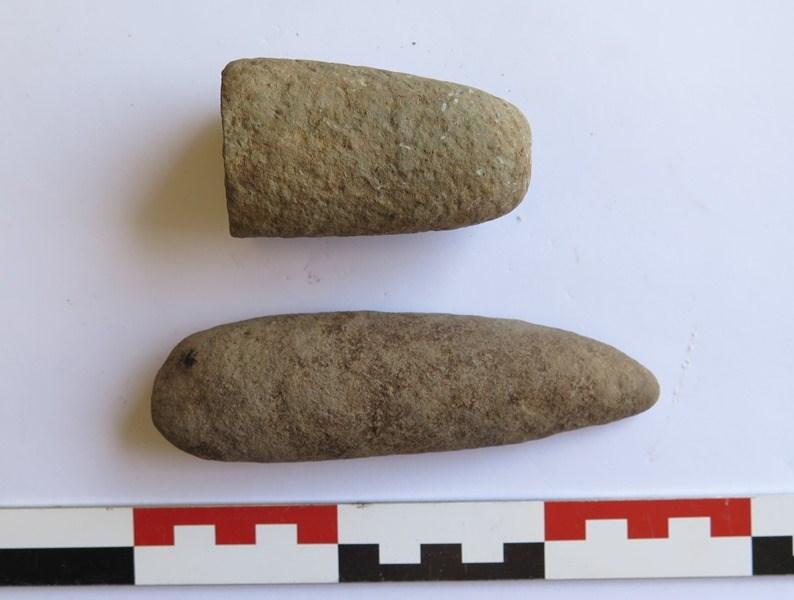 Figur 31: Økser fra R3. Øverst den prikkhuggede trinnøksa. Under: Den prikkhuggede og mulige slipte trinnøksa. Foto: KHM. Det fremkom en rombisk stein med en regelmessig forsenking på lokaliteten.