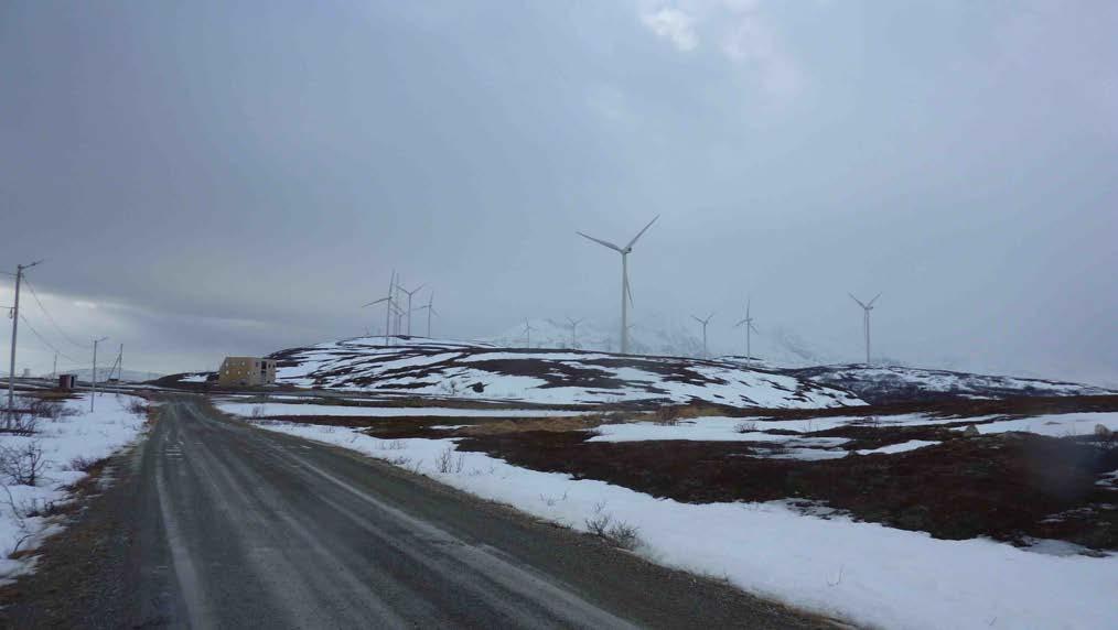 Figur 24: Fakken vindkraftverk er plassert mitt på det største neset på øya. Et typisk vinterbeiteland for rein. Øya har betydelig høyere fjell over det meste som fjellkjeden i bakgrunnen.