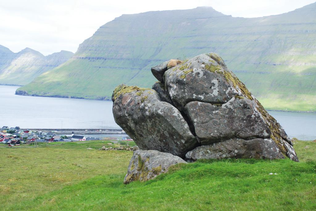 Klovningasteinur. Steinurin er hugtakandi, er sum ein elligamal risi, ið fer undir grønu torvu eins og ættarliðini undan okkum í bygdini. "Eg skar mítt navn... " yrkti Símun av Skarði.