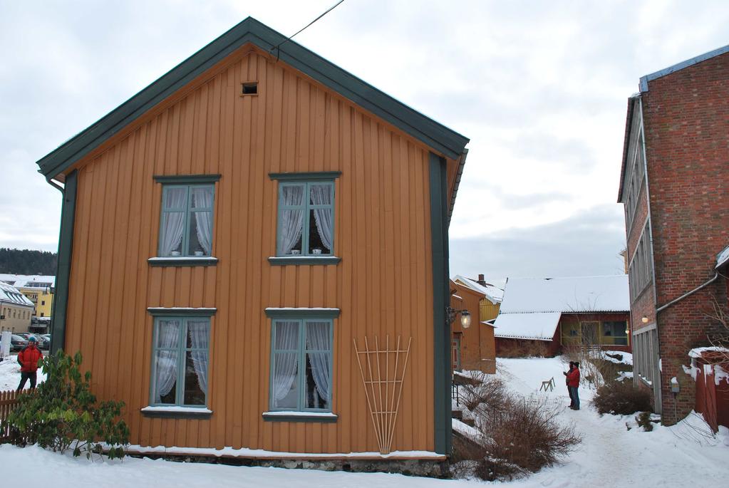 Den siste gavlen ligger tett mot nabohus, men er panelt med grov tømmermannskledning, delvis bare bord fra stokkens ytterside. Har stått umalt inntil for ganske få år tilbake.