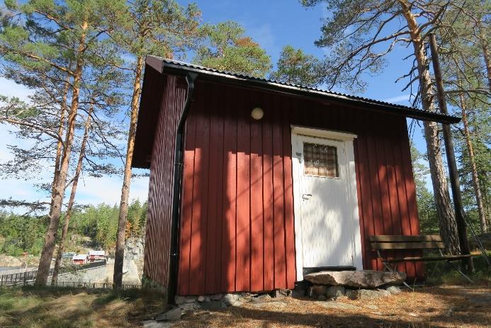 Enkel reisverksbygning, på gråsteinmur, med stående panel, saltak, ett torams vindu og ytterdør.