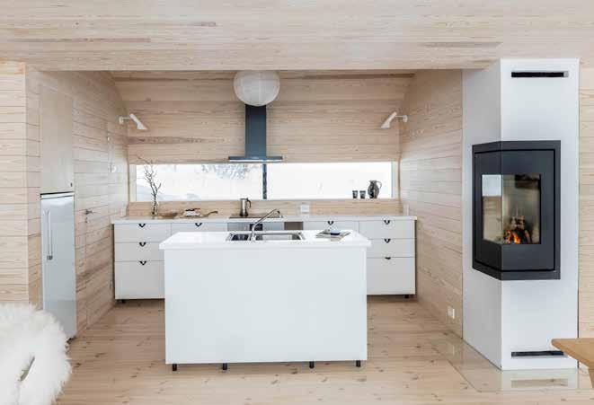 HYTTEBESØK Renskåret innredning. Kjøkkenet består i all enkelhet av underskap og en øy. Vedovnen på hjørnet supplerer gulvvarmen, og utgjør et koselig element i et ellers minimalistisk interiør.