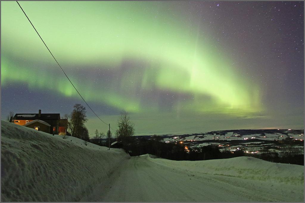 Nordlyset flommer over bygda, her med utsikt nordøstover.