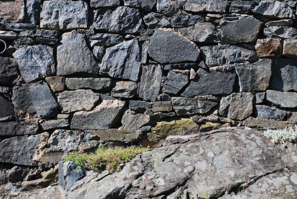 Her er det Flere gamle forstøtningsmurer med bakmur, laget av grov tilhugget stedlig stein.