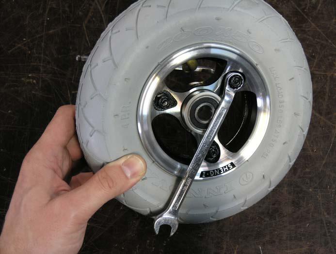banke lett på bolthodet mens man holder på hjulet, for deretter å skrue bolten helt ut.