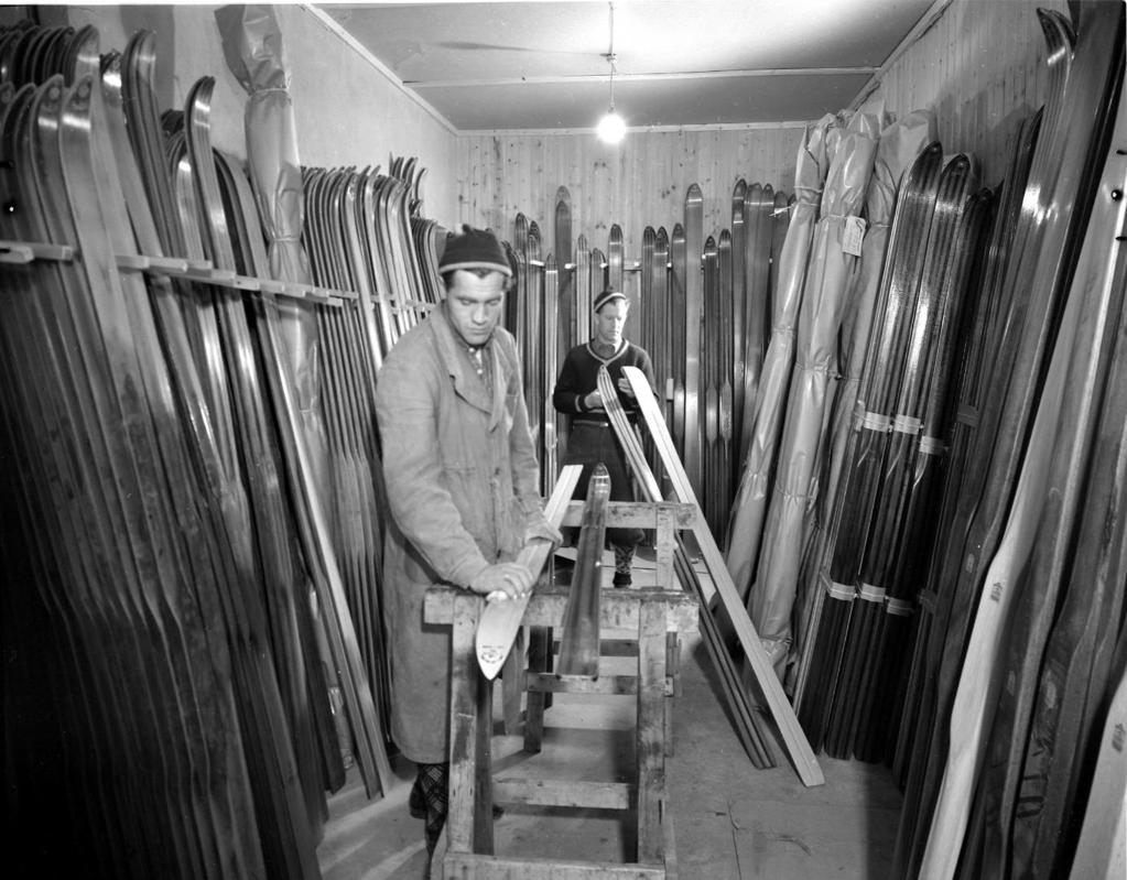 Skifabrikkens to tidligere storhoppere på lageret for de ferdige skiene. Arne Ulland fremst og Birger Ruud bakerst. Bildet er tatt rundt 1950. Foto: Hans Strand. På årsmøte den 25.03.