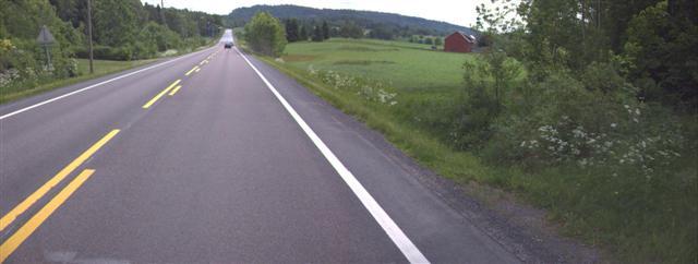 Bilde 16-2: Falkenstenveien sett nordover ved Øvremølla; det er uoversiktlig gang-/ sykkelkryssing ved enden av rekkverket/ støyskjermen, hvor enden også kan være farlig ved påkjørsel av bil.