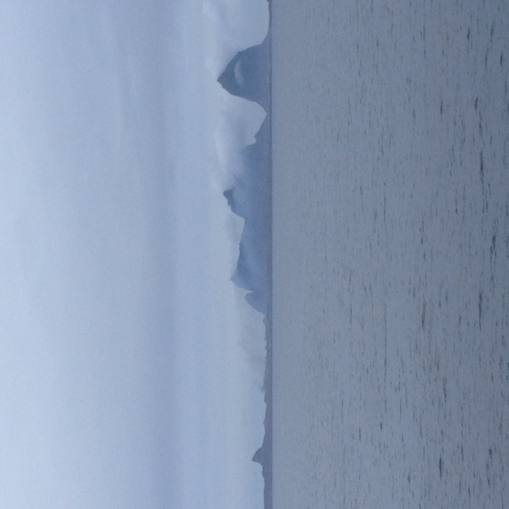 EgetfotoavHusøymedfjellformasjonenpåSannaibakgrunn,tattfrafergen. Langttehavs,ivest,reisteenvakkerformasjonsegoppfrahavet.