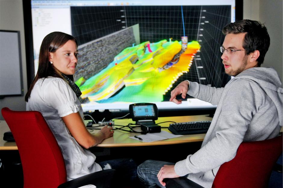 Sissel Grude og Håvard Heldal Lehne studerer gigantskjermen som viser en geologisk tolkning av toppen av Gullfaksfeltet.