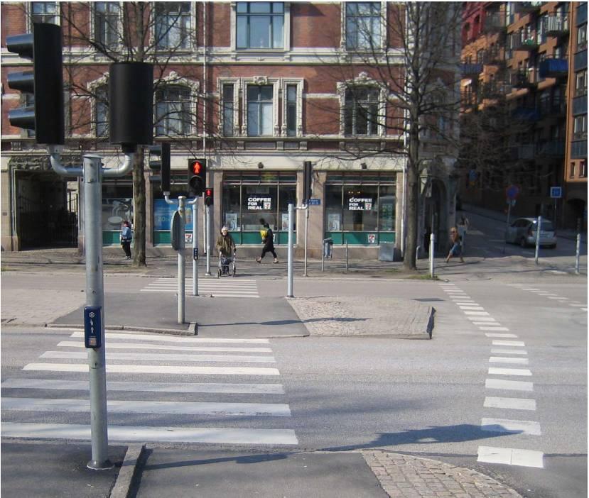 Figur 3 Tilgjengelighetstilpasset trafikksignal med midtplasserte stolper (foto Roland Ahlgren) Øvrige tiltak kan bestå av akustiske enheter som gjør det lettere å finne overgangen