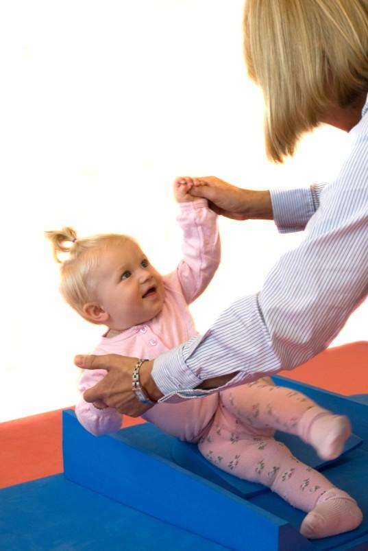 Hold barnet i hendene med tomlene opp, slik at barnet sitter lett skrånet bakover, så forskyver du barnet en gang mot høyre side og en gang mot venstre side.