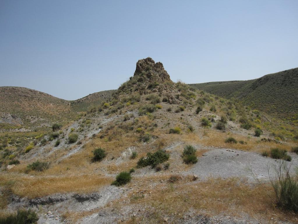 Eroderte rester av tilførselsrøret midt i vulkanen. Den gulfargete steinblokken i venstre billedkant er fra det fossile korallrevet som vulkanen trengte gjennom for 6 millioner år siden.