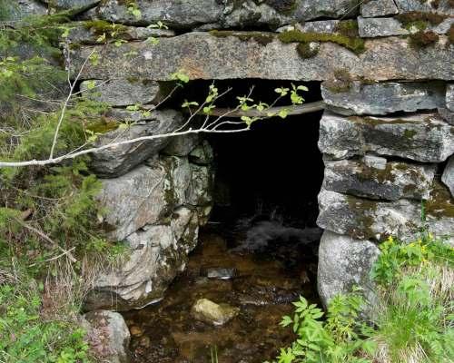 Gjennom Fv30 er bekken lagt i rør, før den går åpent ned skråningen mot jernbanen. Under jernbanen går bekken gjennom en kulvert av stein, før den igjen går åpent ut i Gaula. Figur 6.13.