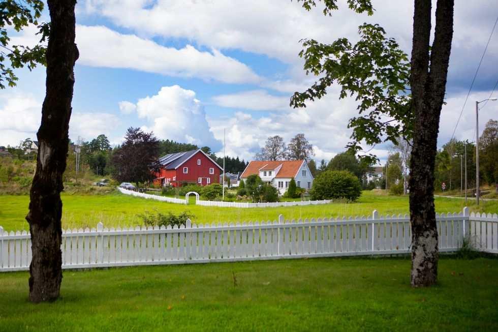 Vi sitter i den store prestegårdshagen, et steinkast fra den gamle kirken. Like bak hagegjerdet ligger kirkegården. Rundt oss ligger store, grønne jorder og hvitmalte, gamle hus i velstelte hager.