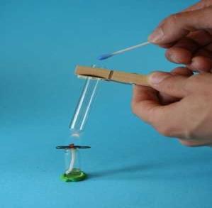 2. Slik lager du en enkel spritbrenner: Sett glasset fast på bordet med en klump modelleire. Putt den lange enden av veken ned i glasset og la bindersen henge på kanten av glasset.
