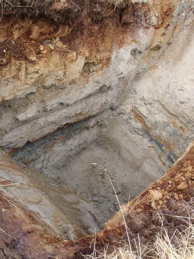 Side: 12 Figur 8 Prøvegrop 4 3.1.5 Prøvegrop 5. Toppen av hullet har steinig grusig masser med aurhelle. Ca 0,7 m under overflaten er det et svart lag ned mot aurhellelaget.