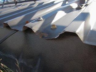 Bilde 50. Detalj som viser at pakninger på skruer på korrugert stålplatetak er stive og morkne. Det er mindre skader på plater ved kanten som har gitt korrosjon. Bilde 51.