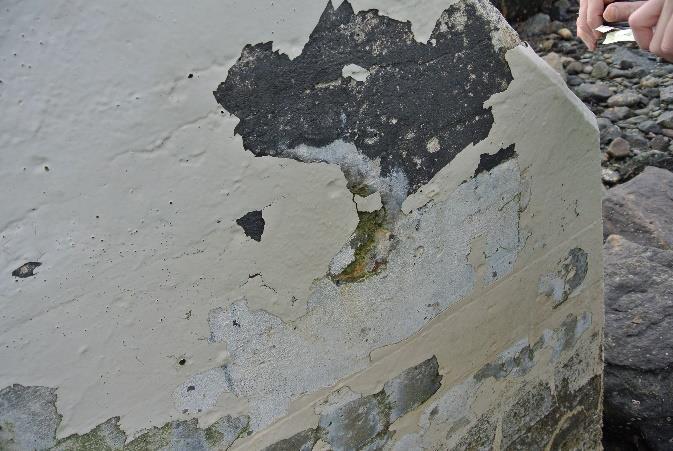 Rustutslag og utstikkende jern nederst på fundamentet stammer trolig fra spiker og armeringsstoler nærme betongoverflaten.